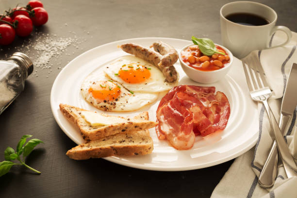 volles englisches frühstück auf weißem teller, schwarzer hintergrund. - pension altersvorsorge stock-fotos und bilder