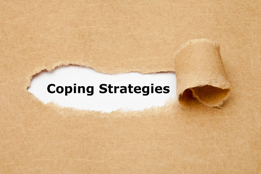 Text Coping Strategies appearing behind ripped paper. Concept about the series of behavioral and psychological skills and actions needed to handle stressful or unpleasant situations.