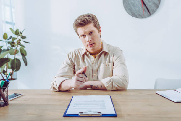 istock handsome recruiter pointing with finger while holding pen near clipboard 1149017867