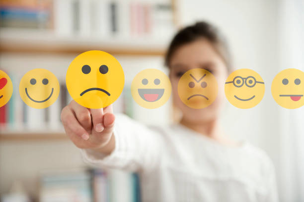 Kleines Mädchen, das die unglückliche Gesicht-Emoji-Ikone auf dem Touchscreen berührt – Foto