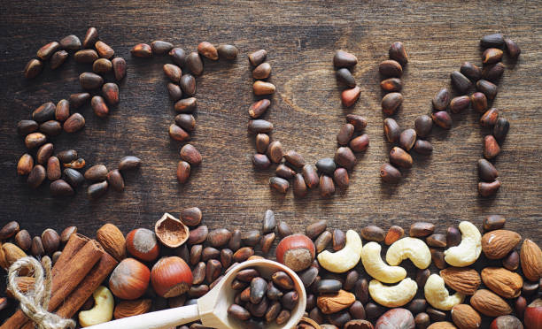 istock Different nuts on a wooden table. Cedar, cashew, hazelnut, walnuts and a spoon on the table. Many nuts are inshell and chistchenyh on a wooden background. 1149026127
