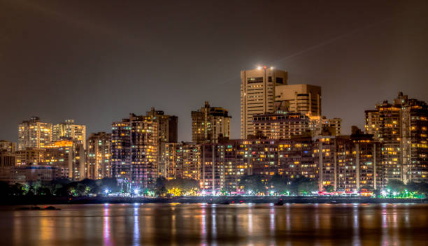 Mesmerizing photo of Colaba Skyline at night, as seen from Nariman Point of Marine Drive.  Buildings, Roadside and Night Market Light reflections may be seen in calm Arabian Sea, is like cherry on top Metropolitan city skyline of a well developed city alongside the coastal area. One of the posh locations in Mumbai which is also termed as the financial capital of India and also is a melting pot. The building depicting the rich culture and extensive use of electricity and posh lifestyle. Tall buildings depicting the population burst. mumbai photos stock pictures, royalty-free photos & images