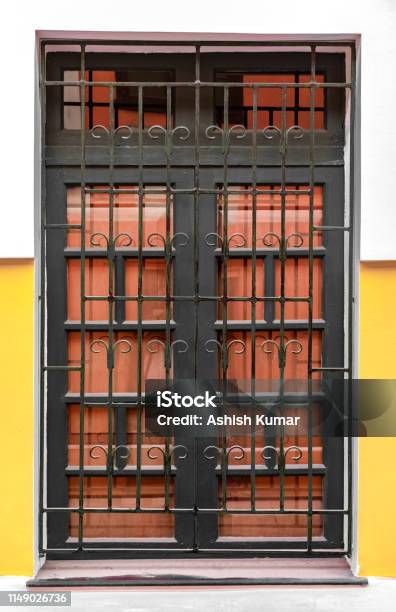 Very Beautiful Corinthian Style Big Window Having Iron Bars With Patterns And Wooden Gate Attached To It A Typical Colonian Era Roman Architecture Image Stock Photo - Download Image Now