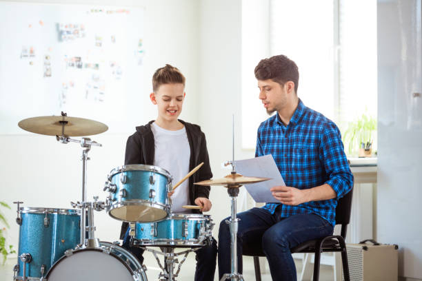 istock Teacher showing sheet to boy while playing drums 1149030825