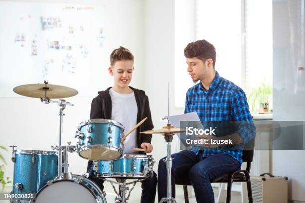 Teacher Showing Sheet To Boy While Playing Drums Stock Photo - Download Image Now - 12-13 Years, 30-34 Years, Adult