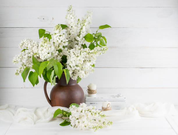 Lilac bouquet in clay jug and candles on background of white wooden planks Lilac bouquet in clay jug and candles on background of white wooden planks in shabby chic style white shabby chic desk stock pictures, royalty-free photos & images