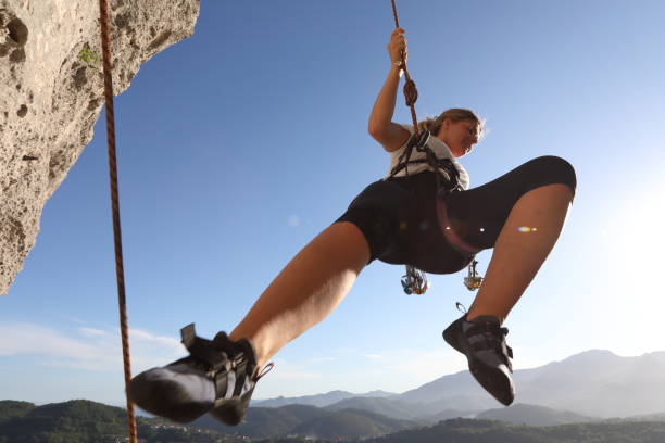 istock Female climber bounces off rock face as she is belayed down route 1149032931