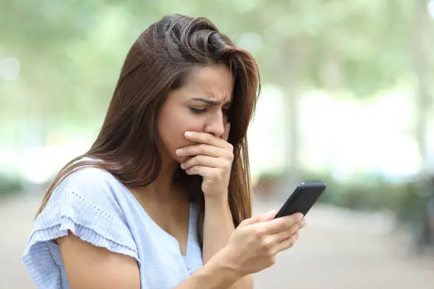 Photo of Sad girl complaining reading bad news on cellphone