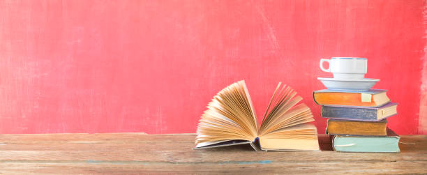istock Open Book and stack of multicolored hardback books with a cup of coffee, reading education, literature, panoramic, good copy space 1149033679