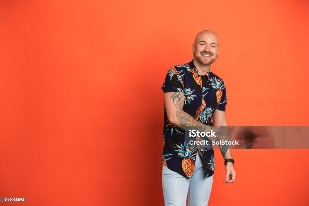 Playful Portrait Portrait a man smiling while looking at the camera in front of an orange studio background. Gay Man Stock Photo