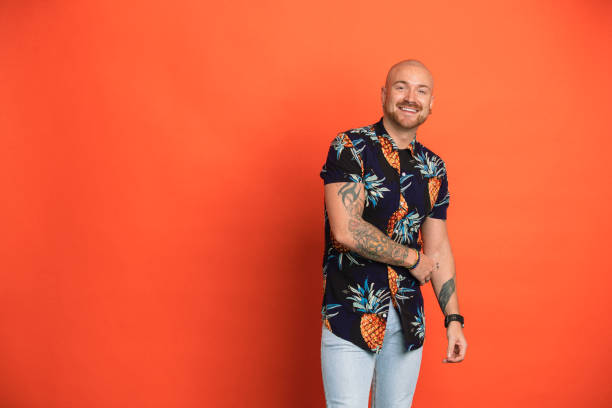 Playful Portrait Portrait a man smiling while looking at the camera in front of an orange studio background. gay man stock pictures, royalty-free photos & images