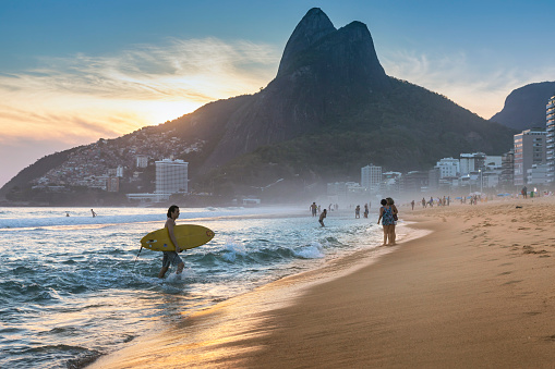 Rio de Janeiro, Brazil - November 16, 2017 : Brazilian young man walking on Ipanema Beach with surfboard at the sunset in Rio de Janeiro, Brazil