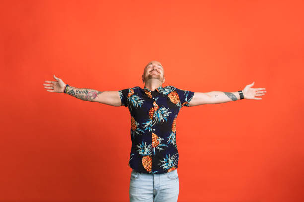Feeling Free Portrait of a man with his head tipped back and arms outstretched standing in front of an orange studio background. arms outstretched stock pictures, royalty-free photos & images