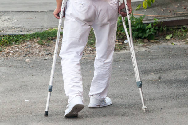 the disabled person walks in park on crutches in clear summer day