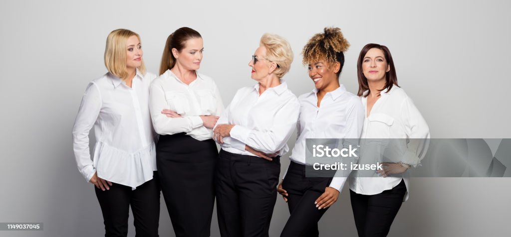Female entrepreneurs against white background Smiling business owners standing side by side. Confident female entrepreneurs are wearing uniform. They are against white background. Businesswoman Stock Photo