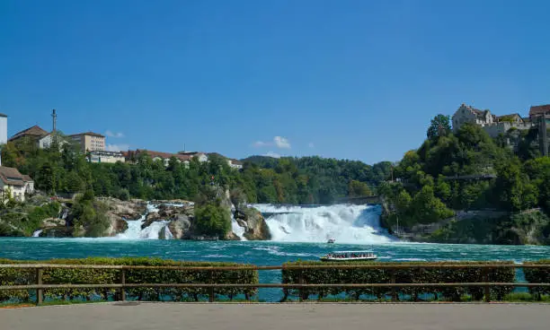 The Rhine Falls of Schaffhausen in Switzerland with their blue water, white cascades, green hills and rocks