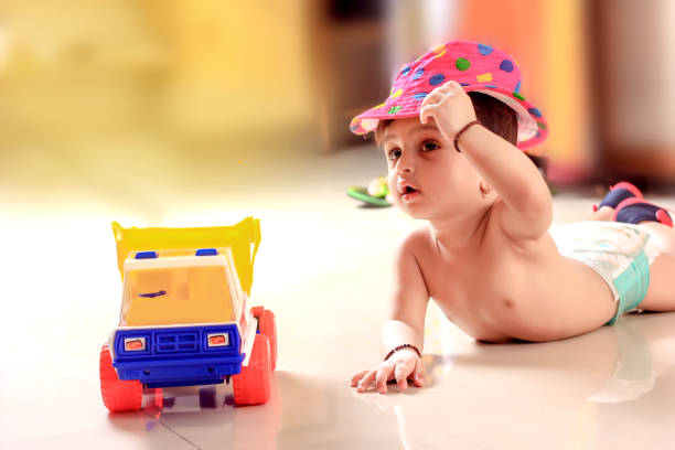 An Asian baby boy, six month old, sitting on baby mat with english alphabet and some toys