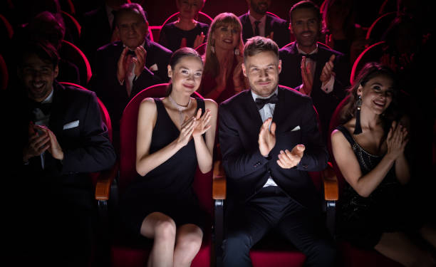 Mature couple clapping while watching opera Mature couple clapping while watching theatrical performance. Happy man and woman are enjoying movie during weekend. They are sitting amidst crowd. opera photos stock pictures, royalty-free photos & images