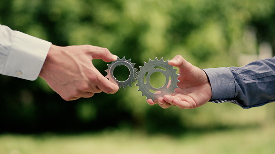 Two businessmen trying to match cog gears. Flexibility in business