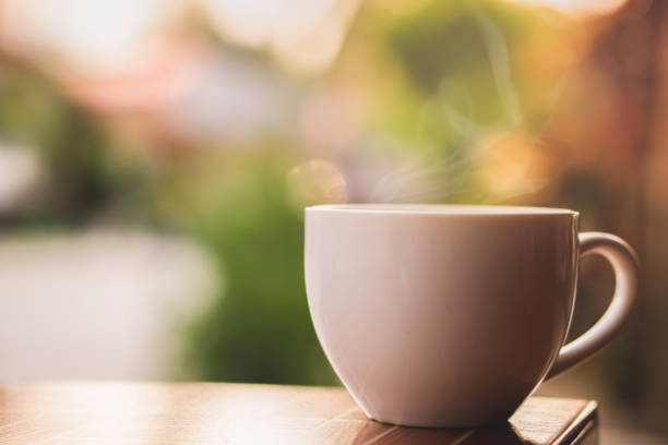 heiße kaffeetasse mit rauch am morgen - heißes getränk stock-fotos und bilder