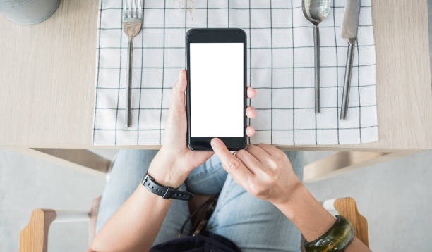 chiudere la mano tenendo schermo bianco vuoto sul tavolo del ristorante - qr code marketing mobile phone coding foto e immagini stock