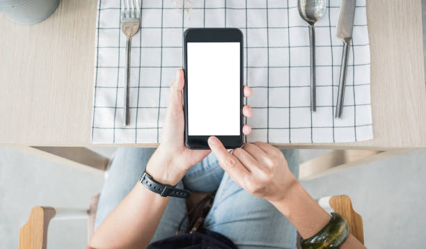 close up hand holding white blank screen over restaurant table