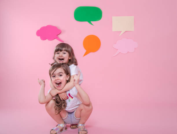 beautiful woman hugging adorable daughter while soap bubbles flying around on pink background