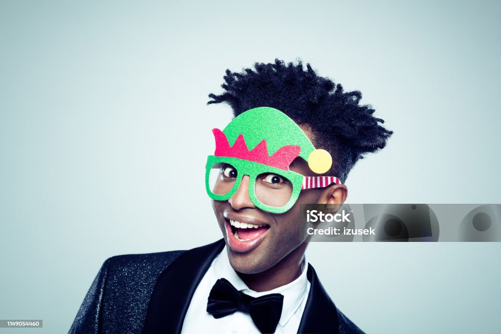 African man wearing funny christmas mask Close up of a happy young african man wearing funny christmas mask on gray background Humor Stock Photo