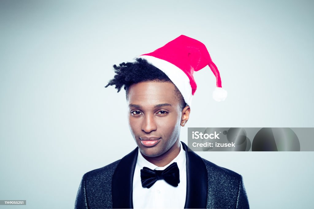 African man with santa hat Portrait of young man wearing santa hat. African man with santa claus hat and looking at camera on gray background. 20-29 Years Stock Photo