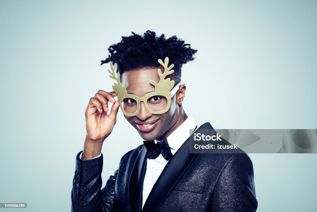 Funny christmas portrait of young man Funny christmas portrait of handsome young man. African man wearing reindeer antlers glasses on gray background. Antler Stock Photo