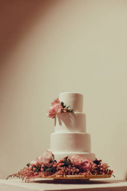 istock White wedding cake decorated with  roses on the table. 1149057592