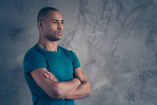 istock Profile side view portrait of his he nice-looking attractive strong powerful content dreamy guy wearing trendy blue t-shirt folded arms isolated over gray industrial concrete wall 1149057685