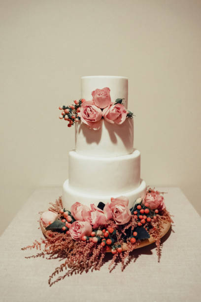 istock White wedding cake decorated with  roses on the table. 1149058118