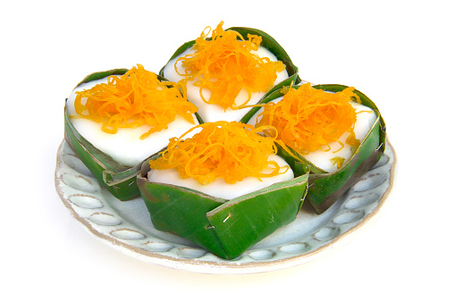 Thai dessert sweets pudding filling with sago and coconut milk topping sprinkle on side with golden threads on banana leaf  cup side view isolated on a white background