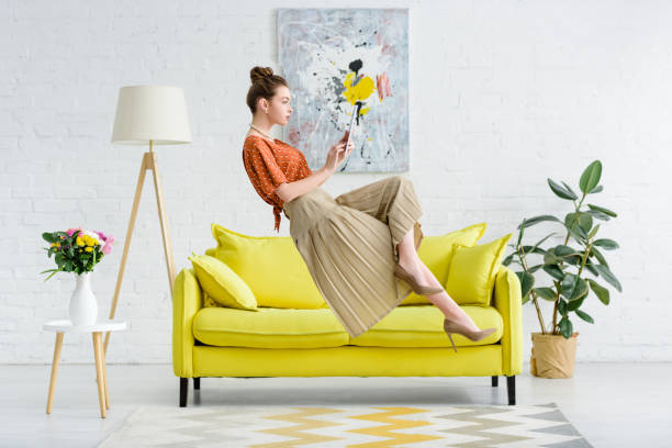 elegante mujer joven levitando en el aire y el uso de la tableta digital en el salón - levitación fotografías e imágenes de stock