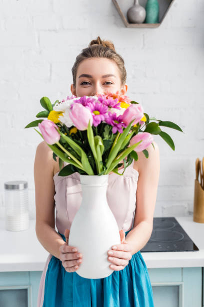 hübsches mädchen mit obskuren gesicht versteckt hinter strauß von wildblumen in vase - tulip bouquet stock-fotos und bilder