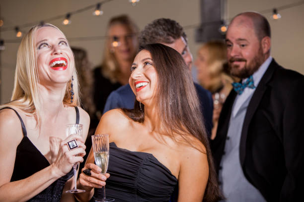 istock Two Laughing Women Being Watched by Men at Party 1149064580