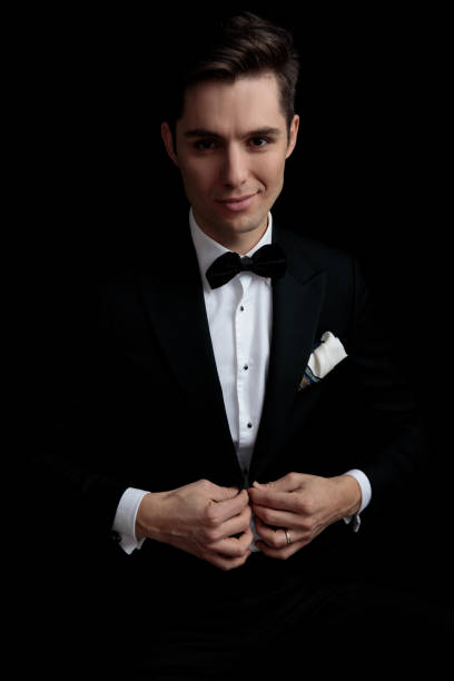 istock luxury smiling man in black tuxedo buttoning his lounge jacket 1149066325