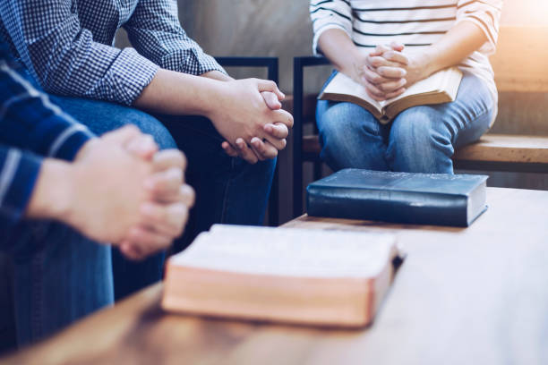 Christian friends pray together Christian group are praying together around wooden table with holy bible apostle worshipper photos stock pictures, royalty-free photos & images