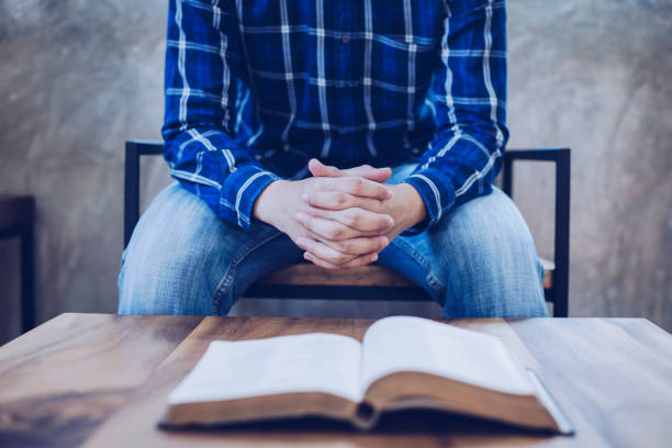 A man sitting on wooden chair praying to God stock photo