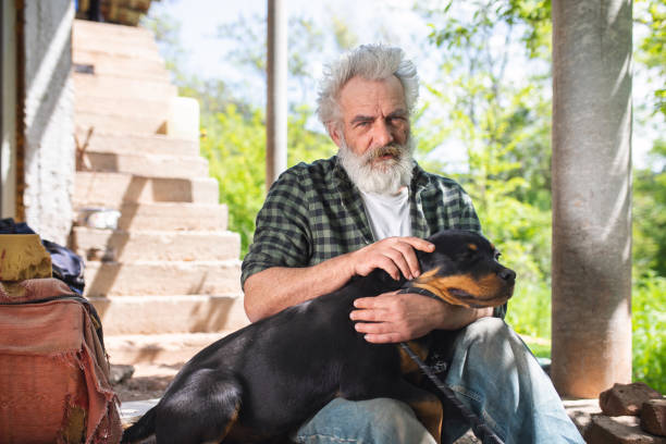 istock Old man stroking his dog while resting on a staircase in his home yard 1149070862