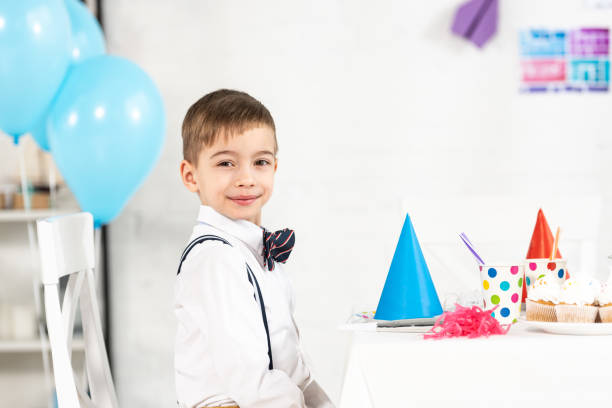 istock adorable boy sitting at party table and looking at camera during birthday celebration 1149074829