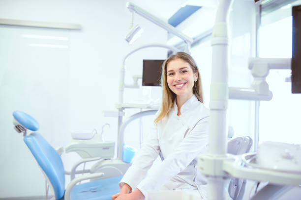 A dentist in gloves holds a syringe during preparation for a dental procedure in a clinical setting. This sterilized equipment is essential for patient care.