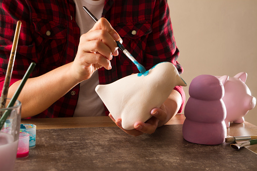 Adult woman hands painting clay coin banks