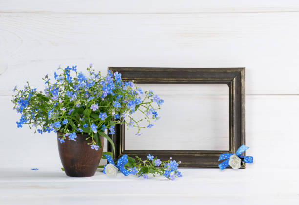 Forget-me-not flowers bouquet and photo frame Me-nots flowers bouquet in clay vase and gilding photo frame on white wooden shabby board. Home interior. white shabby chic desk stock pictures, royalty-free photos & images