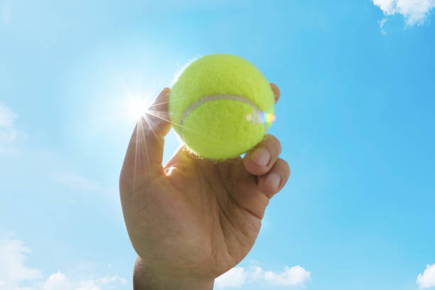 青い空に対して黄色い tennisball を持っている人。スポーツ、競争および適性の概念。 - tennis ball ball isolated sport ストックフォトと画像