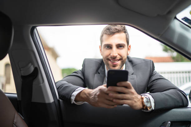 istock Businessman leaning on car window holding a cellphone 1149080555