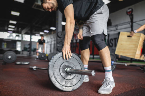 istock Strong weightlifter adding weights to his barbell 1149080791