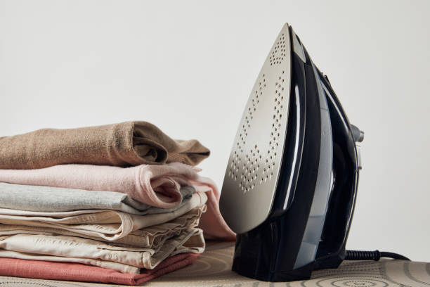 istock Iron and folded ironed clothes on ironing board isolated on grey 1149083336