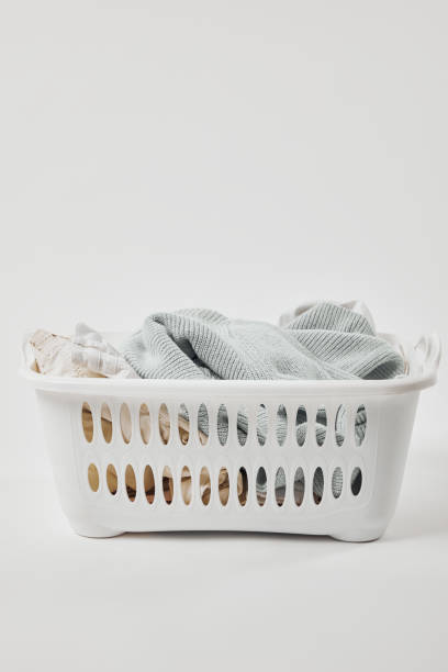 istock White plastic laundry basket with dirty clothes on grey 1149083376
